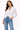 Woman wearing a white denim jacket and blue jeans on a white background