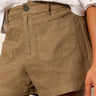 A woman wearing semi high rise brown shorts and a white top