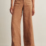 a woman wearing light brown wide leg pants and studded black sandals