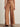 a woman wearing light brown wide leg pants and studded black sandals