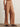 Brown linen pants worn by a person on a neutral background