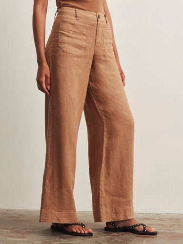 Brown linen pants worn by a person on a neutral background