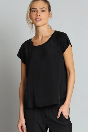 Woman wearing a black top and pants against a gray background