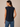 A woman wearing a deep navy blouse on a neutral background