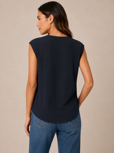 A woman wearing a deep navy blouse on a neutral background