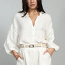 Woman wearing a white outfit with a belt on a gray background