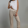 A woman wearing cropped linen beige pants and a white top on a neutral background 