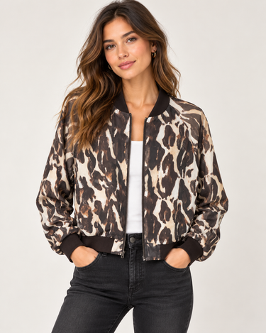 a woman wearing a reversible baseball leopard jacket with black jeans on a neutral background.