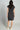 Woman wearing a dark gray dress against a plain background