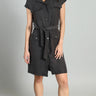 Woman wearing a black sleeveless dress with buttons on a gray background