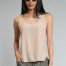 A woman wearing a beige satin tank with a split hem and grey trousers  on a studio background.
