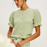 a woman wearing a green short sleeve sweater with ruffle trimmed puff sleeves