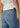 Person wearing blue jeans and a white top against a neutral background