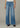 Person wearing blue flared jeans on a neutral background