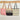 Three woven bags hanging on a wooden rack against a plain wall.