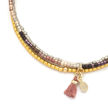 Multicolored beaded bracelet with a tassel charm on a white background