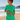 Woman in green outfit standing on a beach with ocean view