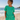 Woman in jade green outfit standing on a beach with ocean in the background