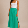 A woman wearing a jade midi skirt and white tank on a neutral background