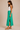 a woman wearing a midi green maxi skirt and white tank on a neutral background