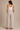 a woman wearing beige colored pleated pants and a white tank