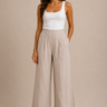 a woman wearing beige colored pleated pants and a white tank