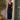 Woman wearing a navy blue dress standing outdoors next to a wooden door.