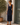 Woman wearing a navy blue dress standing outdoors next to a wooden door.