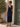 Woman wearing a navy blue dress standing outdoors next to a wooden door.
