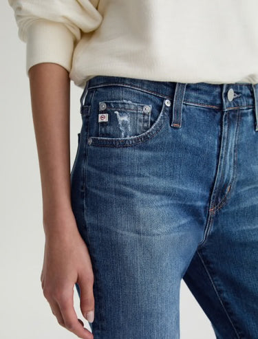 Close-up of blue jeans featuring side pocket details with a neutral background