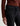 A woman wearing slim straight jeans in black with black boots and a maroon long sleeve tee on a white background.