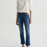 Person wearing a white sweater, blue jeans, and brown shoes on a white background