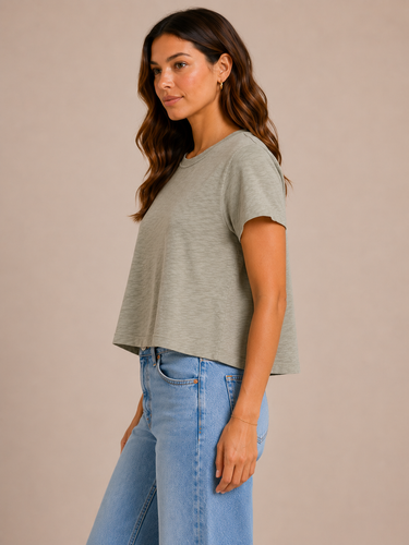 a woman wearing a crewneck cropped boxy fit tee in pale army green with jeans on a neutral background