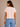 a woman wearing a crewneck cropped boxy fit tee in pale pink with jeans on a neutral background