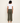 Woman wearing a white t-shirt and green wide-leg pants on a plain background