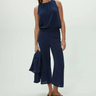 Woman wearing a navy blue sleeveless top and cropped wide-leg pants on a white background