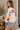 A woman wearing a white sweater with “Merry Christmas” written along the arms and shoulders in colorful letters.