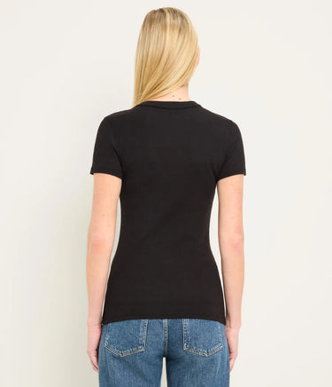 A woman viewed from the back wearing a fitted black short-sleeve crew-neck t-shirt and blue jeans, set against a plain off-white studio background.