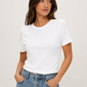Woman wearing a white t-shirt and blue jeans against a plain background