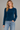 a woman wearing a brushed yarn crewneck sweater in a deep blue and blue jeans