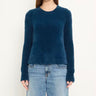a woman wearing a brushed yarn crewneck sweater in a deep blue and blue jeans on a white background.