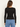 A woman wearing a black long sleeve top with blue jeans on a white background