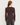A woman viewed from the back wearing a fitted long-sleeve crew-neck top in dark brown, paired with dark gray jeans, against a light gray studio background.