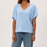 Woman wearing a light blue top and jeans on a plain background