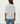 Person wearing a white oversized shirt and blue jeans on a plain background