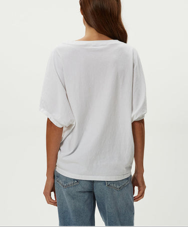 Person wearing a white oversized shirt and blue jeans on a plain background