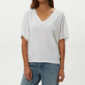 Woman wearing a white oversized t-shirt and blue jeans on a plain background