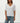Woman wearing a white oversized t-shirt and blue jeans on a plain background