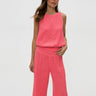 Woman wearing a pink textured top and pants on a white background