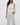 Woman wearing a white sleeveless top and pants on a plain background